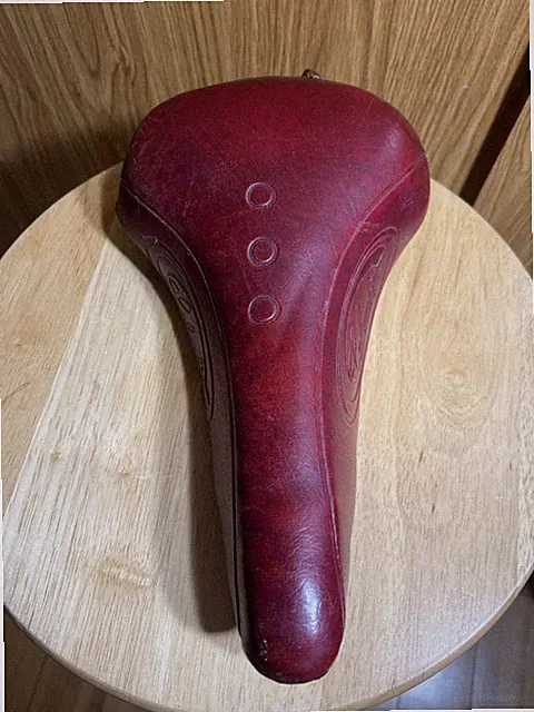 vintage red bicycle saddle appears consistent with old school BMX parts Persons